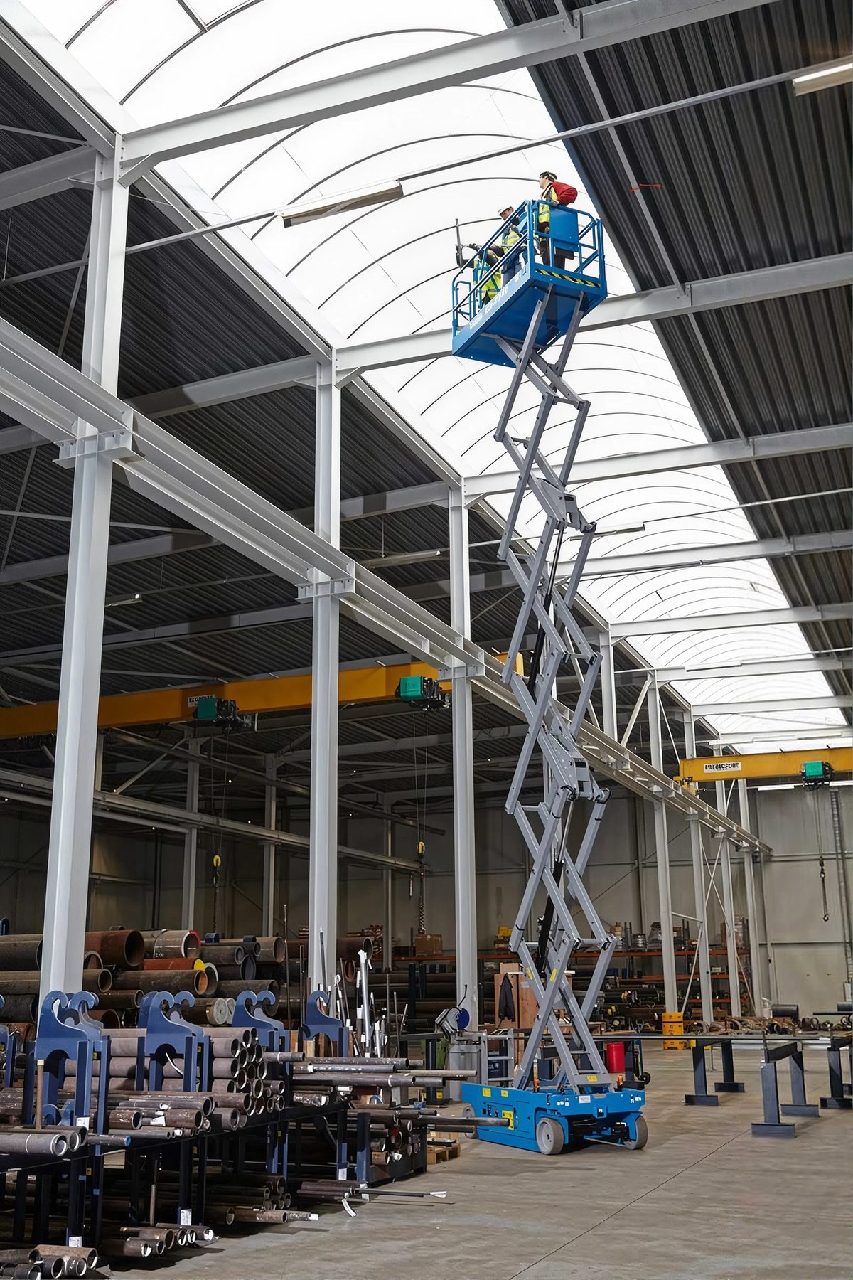 Scissor lift raised inside a steel-framed warehouse under construction